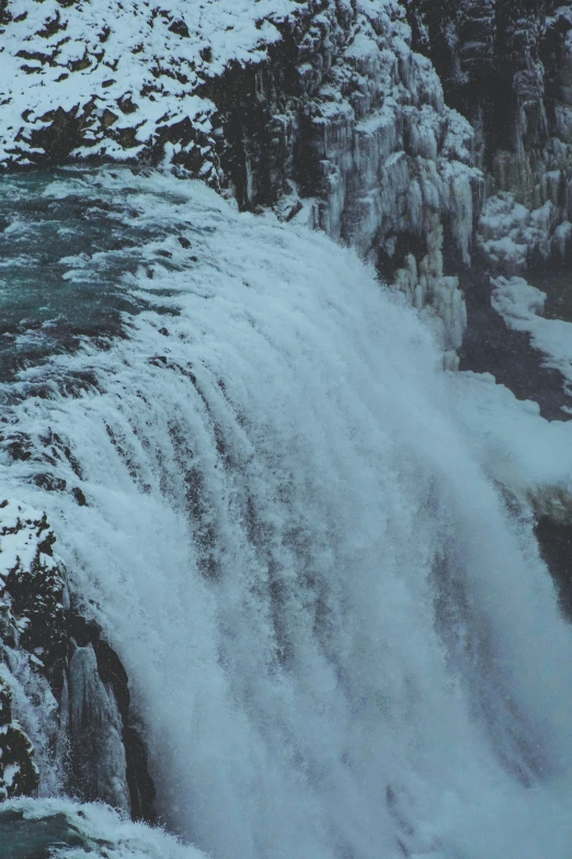 water fall next to large ice covered cliff