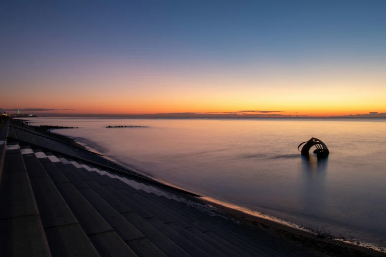 a beach scene at dusk with a boat in the water