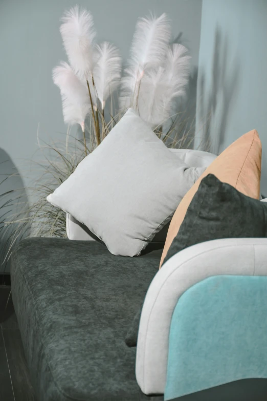 a grey bed with white pillows and white feathers