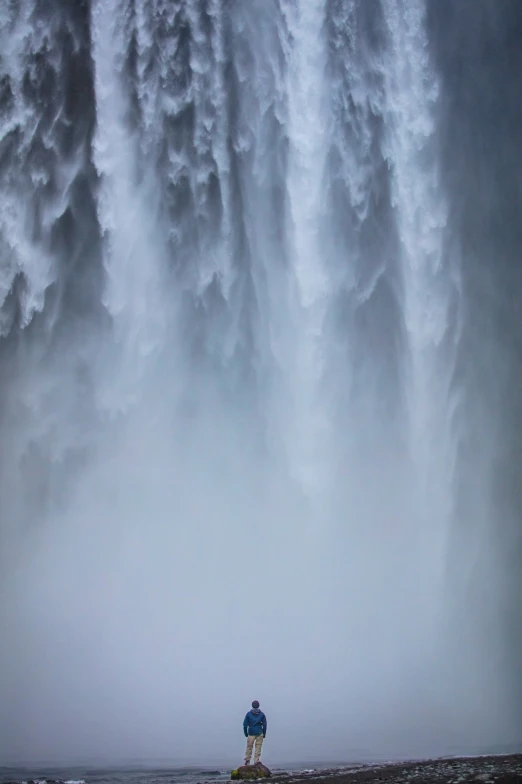 two people standing at the base of a waterfall