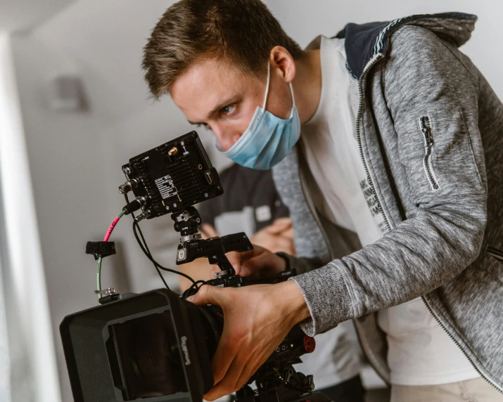 a man in a mask looking over a tripod