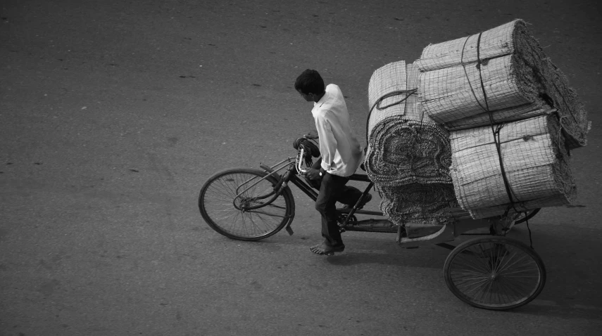 a person on a bike and carrying stacks of straw to go