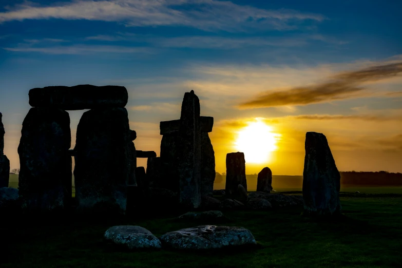 the sun is setting over stonehenge standing in the grass