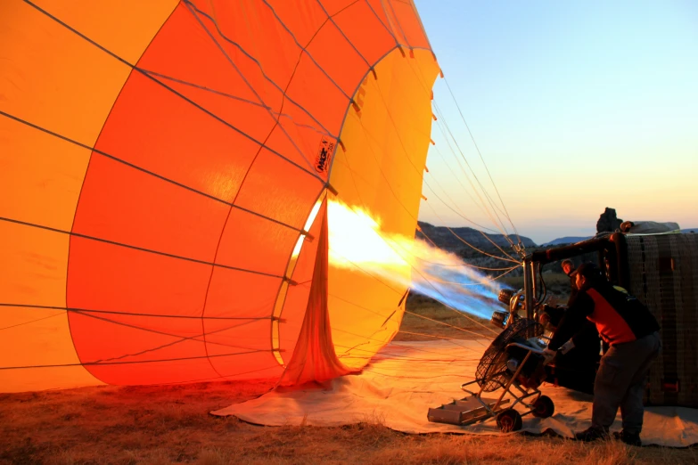 two men near an orange  air balloon with water pouring