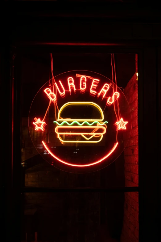 neon burger sign inside a dark room with brick wall