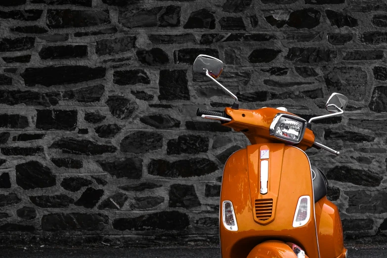 an orange moped is parked against the wall