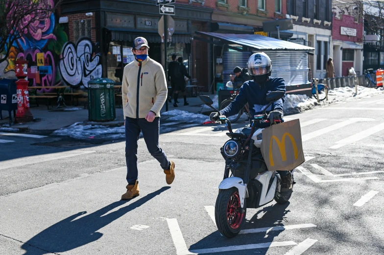 a person with an empty box is on the back of a motorcycle in a city street