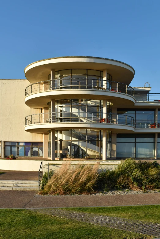 a large modern round home with balcony overlooking the water