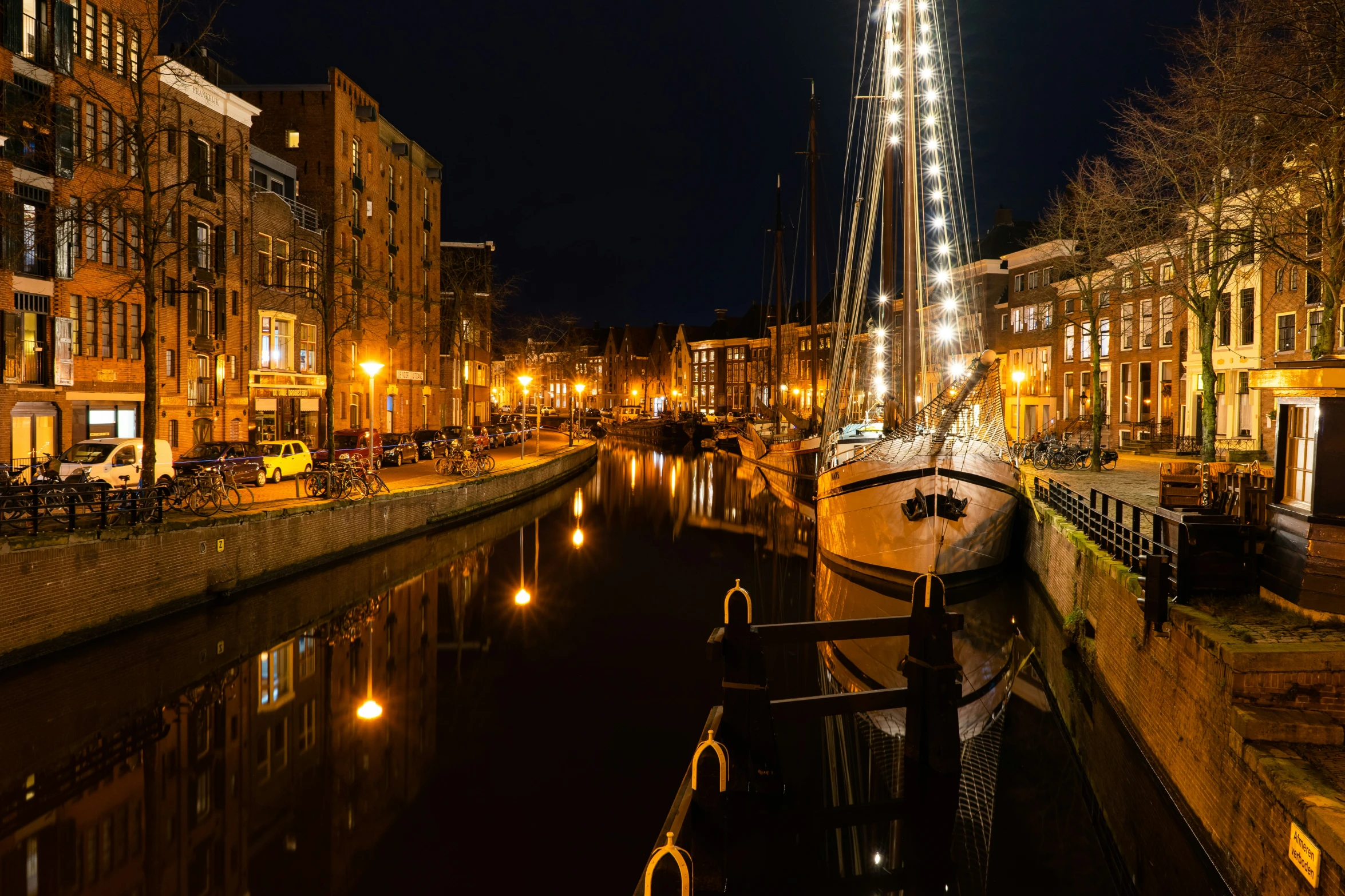 a harbor at night, with buildings lining it and lights on the boats