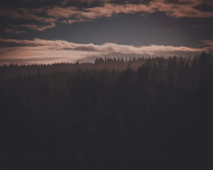 a landscape with the sun low to a very cloudy sky