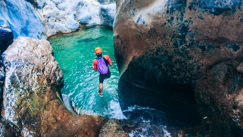 a person wading through a body of water between two cliffs