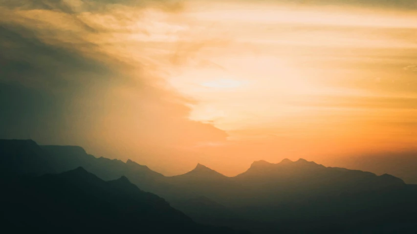 sunset with the mountains in silhouette and clouds overhead