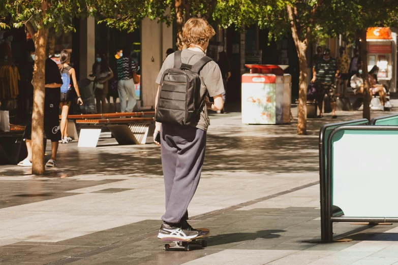 a person skateboards down a sidewalk while a person holds on to the board