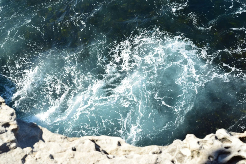 water crashing into some rocks in a bay