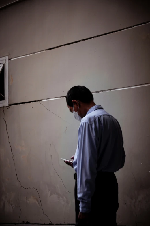 a man standing against a wall using his phone