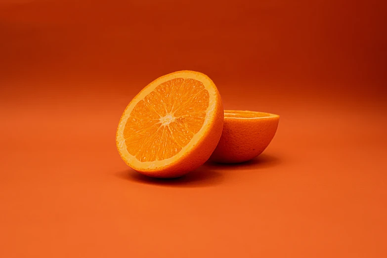 an orange is sliced into two halves on a red surface