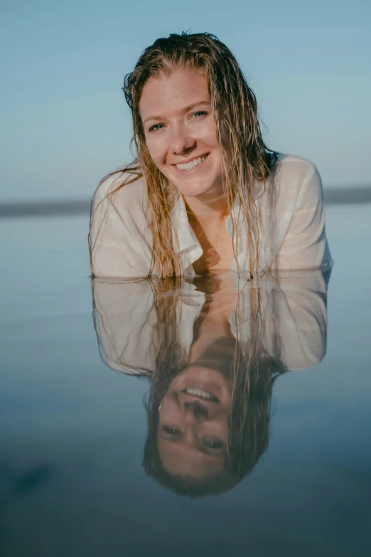 a woman lying on top of a lake surrounded by the ocean