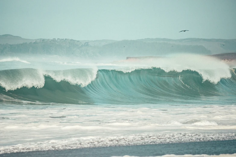 a large wave crashing in on a beach