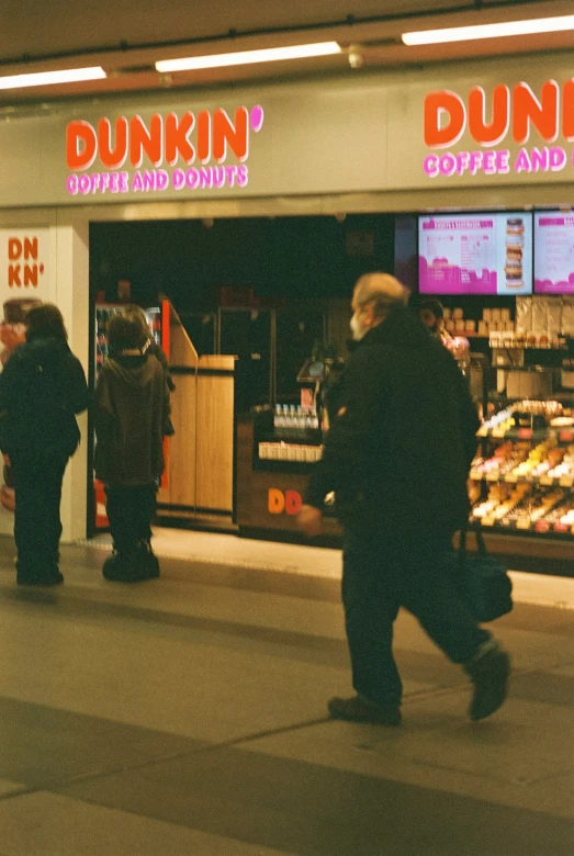 people in a dunkin donuts restaurant are walking down the sidewalk