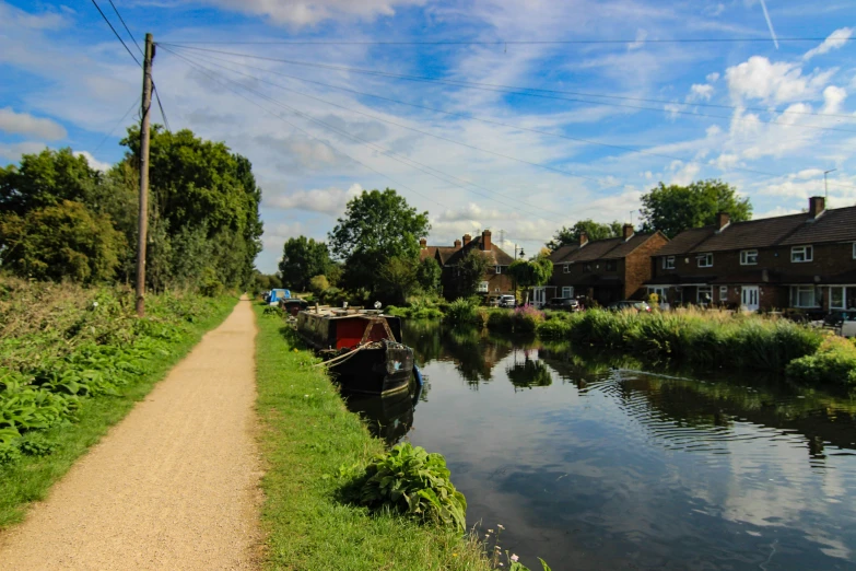 a small waterway running between houses on a dirt road