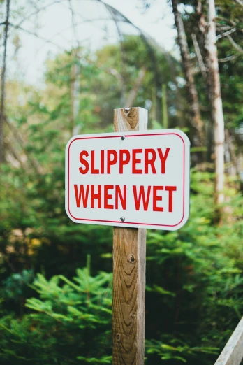 a red and white sign with the words slippery when wet on it