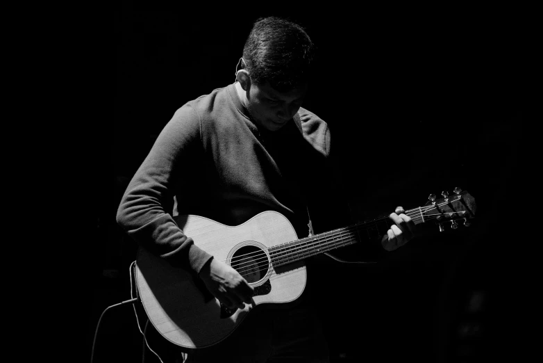 a woman holding a guitar standing against a black background