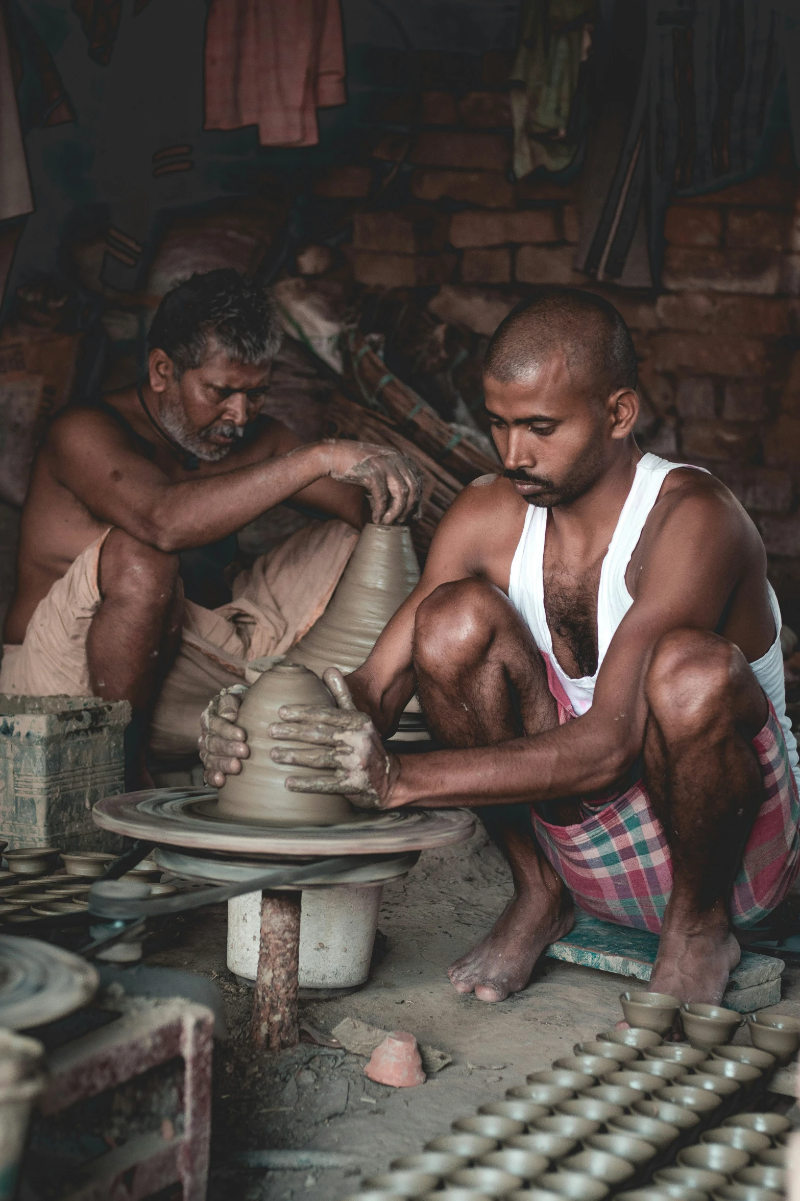 two men are making ceramic pots in a village