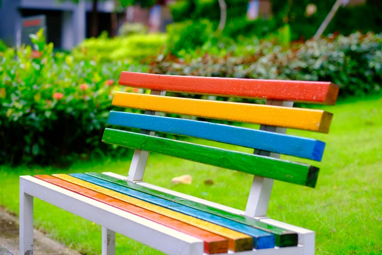 an colorful park bench sits on the grass