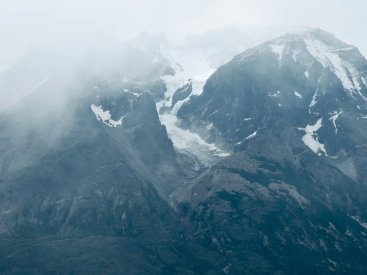 a large mountain range in the fog filled sky