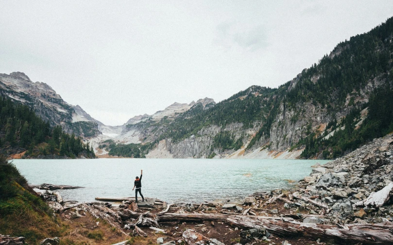 a person standing by the edge of a lake in a wilderness