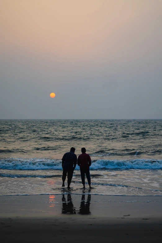 two people on the beach are holding onto each other