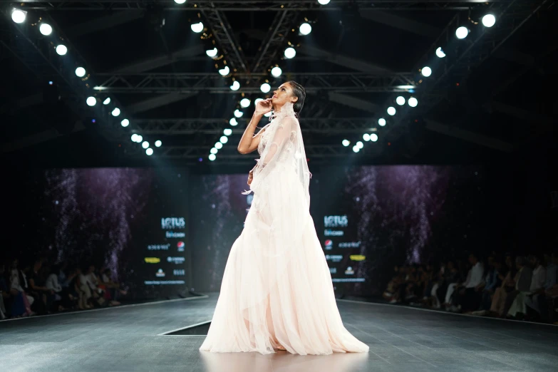 a model wears a dress as she walks down the runway