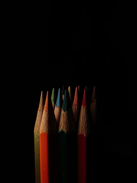 a bunch of pencils are standing together in the dark