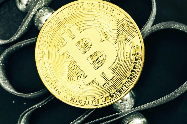 a gold bitcoin is on a black surface