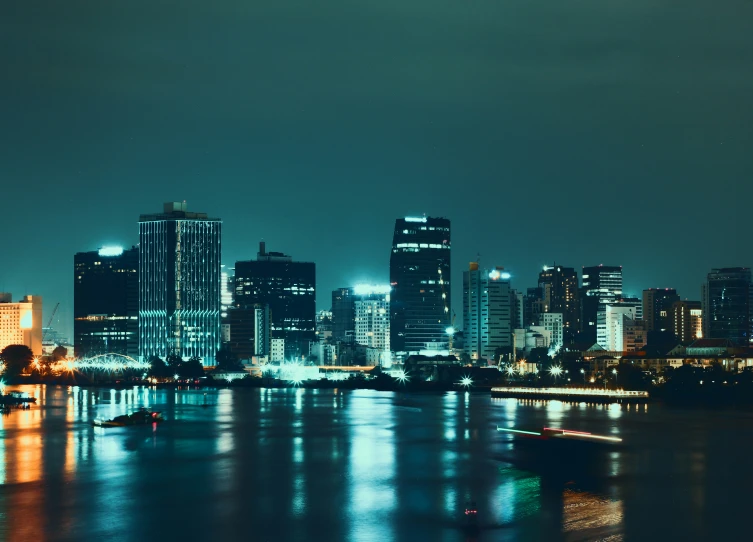 a city at night next to the water with lights on