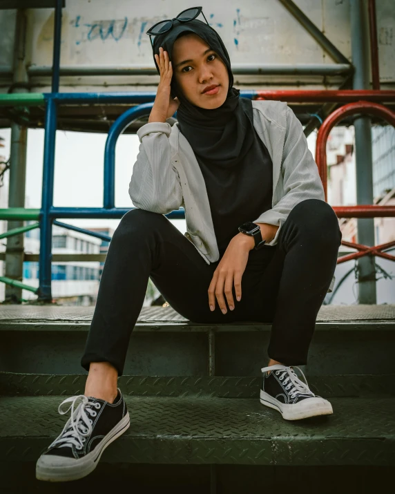 a woman wearing a hijab is sitting down on some stairs