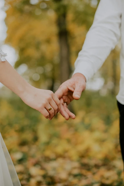 an engaged couple holds hands as the man holds the woman's hand