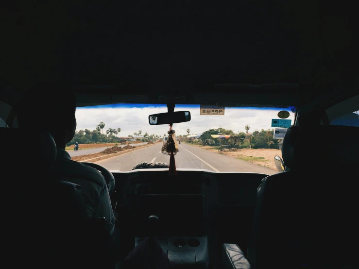 two people sitting in a car driving on a street