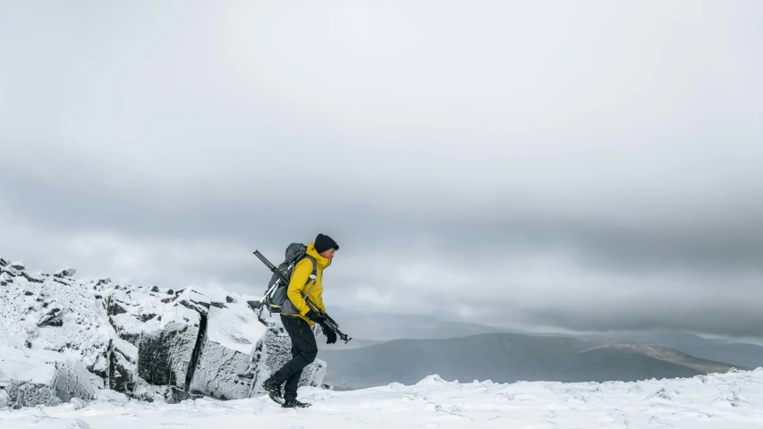 a man in yellow coat walking up a snowy hill