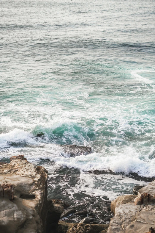 a person standing on top of a rocky beach next to the ocean