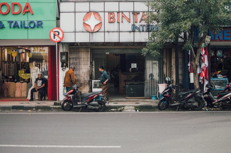 three motor scooters are parked in front of a small store