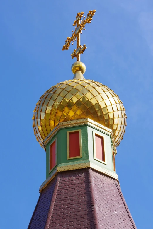 a gold dome with windows and a metal figure atop