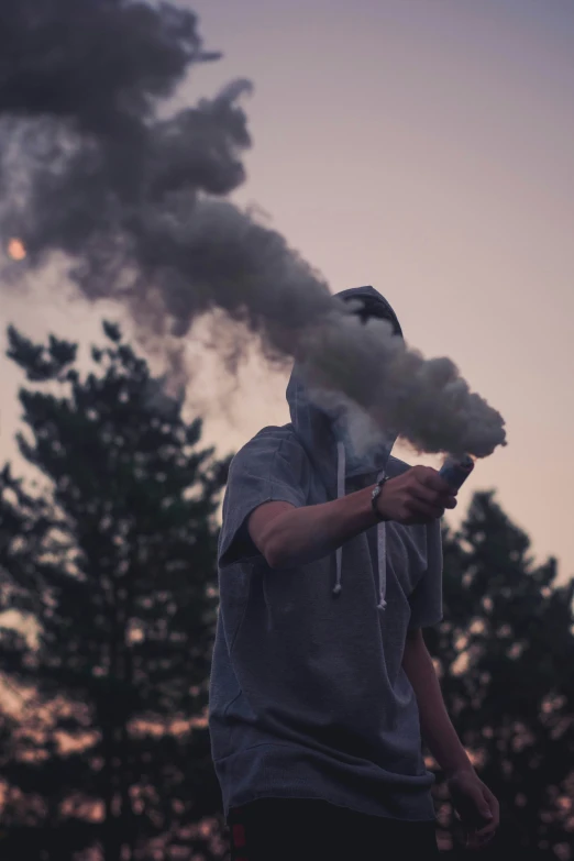 a man holding a cigarette in front of a dark sky