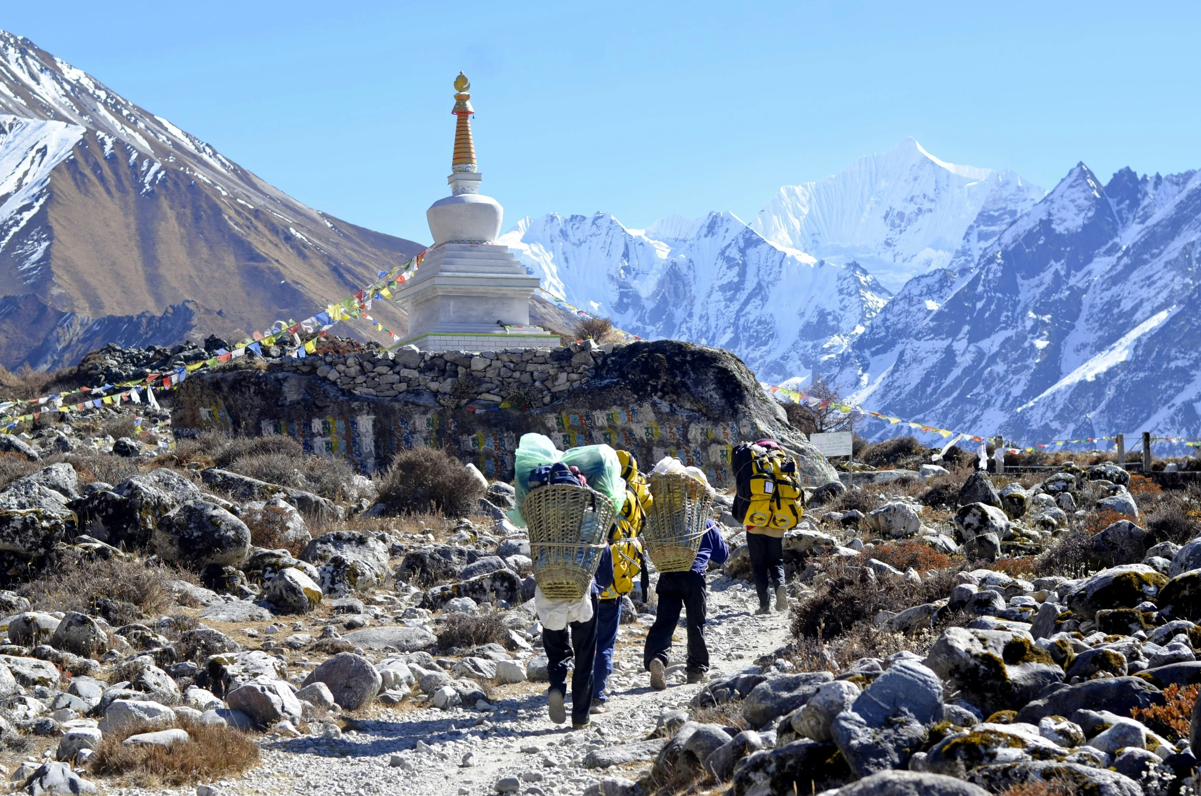 people walking up a mountain side trail with mountains in the background