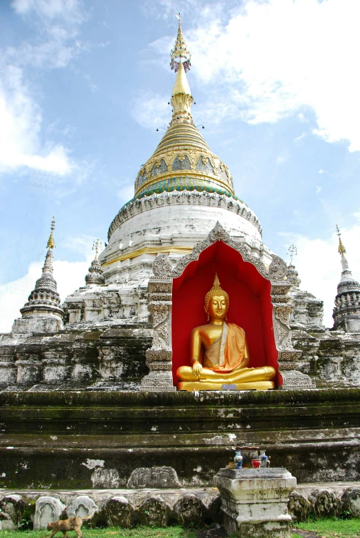 large golden statue sitting on a red platform next to buildings