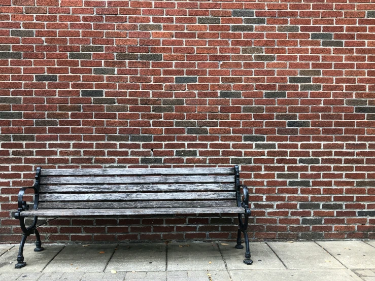 a bench sitting in front of a brick wall