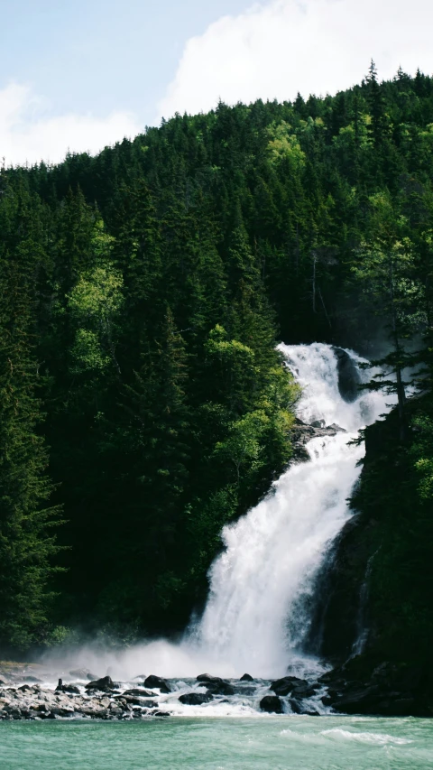 a waterfall with water flowing over rocks in a forest