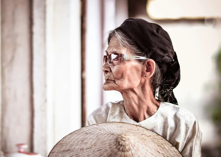 an older woman is holding a large round fan