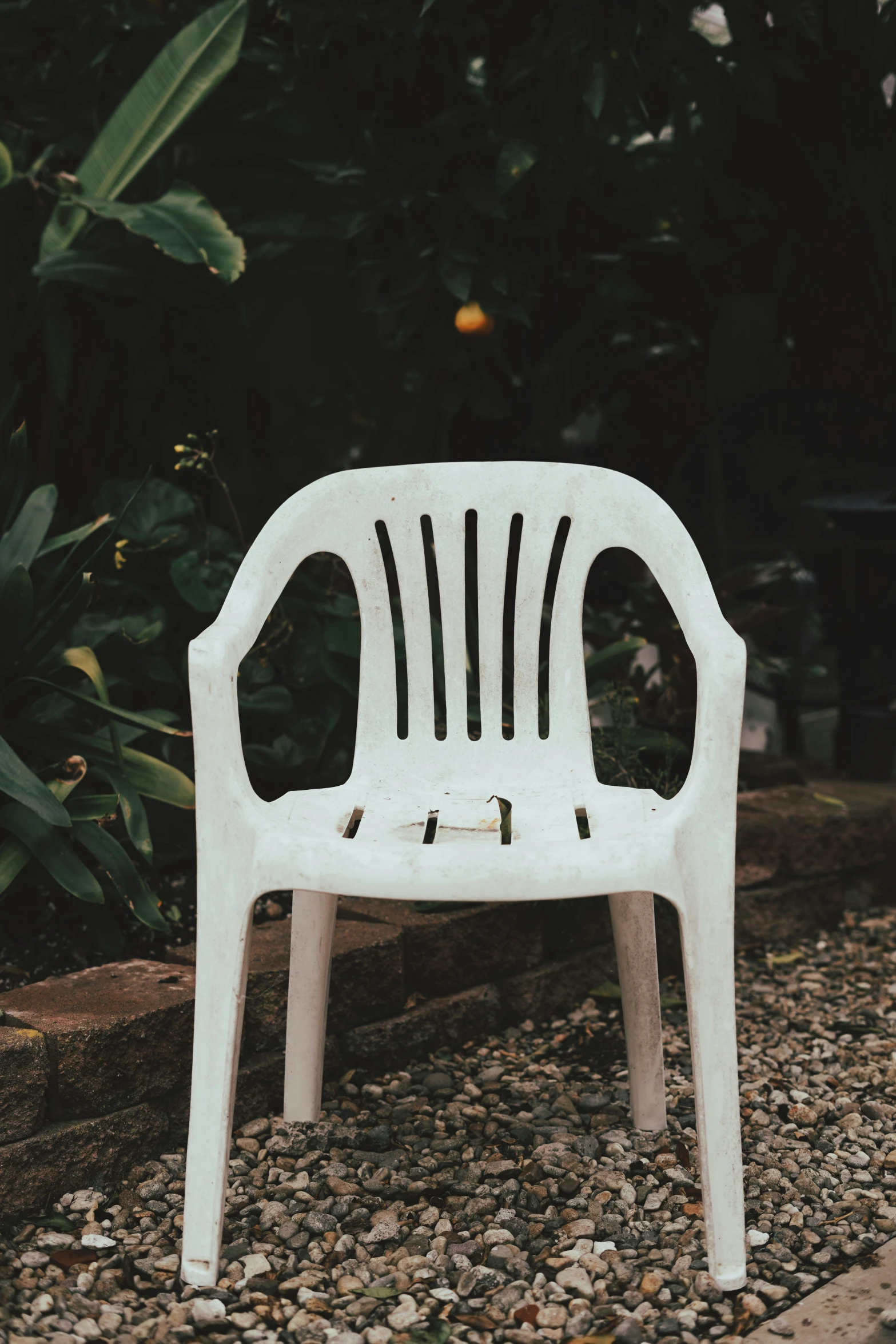 the plastic chair is sitting out on the stone path