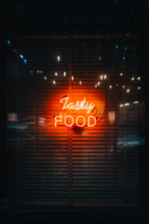 a neon sign that says tasty food in front of a window